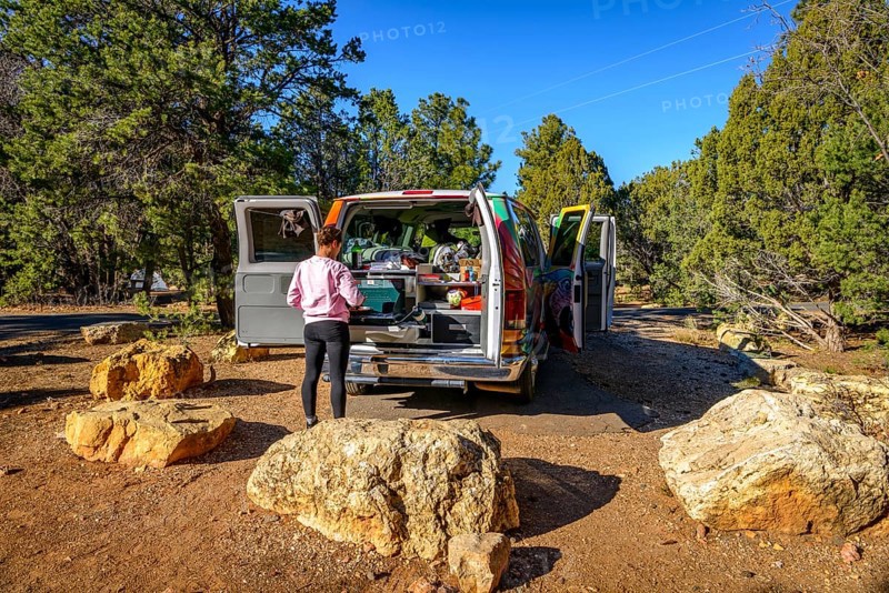 Young woman cooking at the gas stove of a camping van