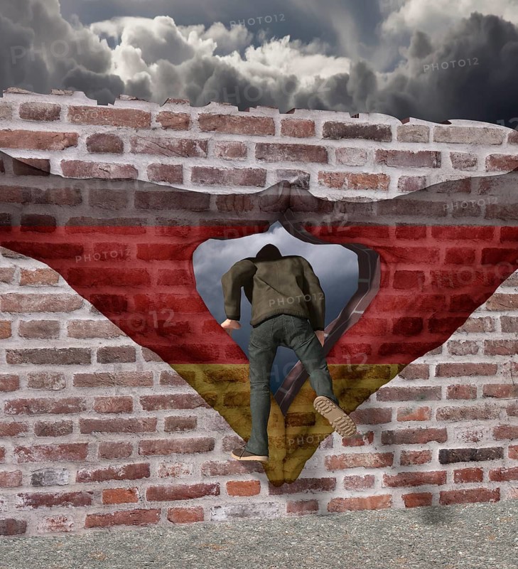 Man climbs through Merkel diamond on a wall with German flag
