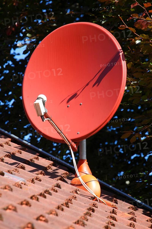 Red satellite dish on a roof of a residential house