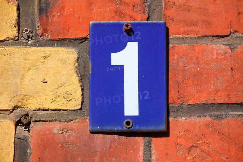 Blue house number plate number 1 on red brick wall