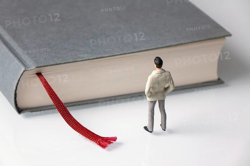 Male figure stands in front of grey book