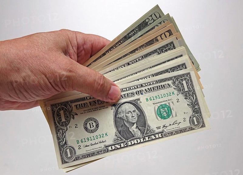 Hand holds bundles of U.S. dollars