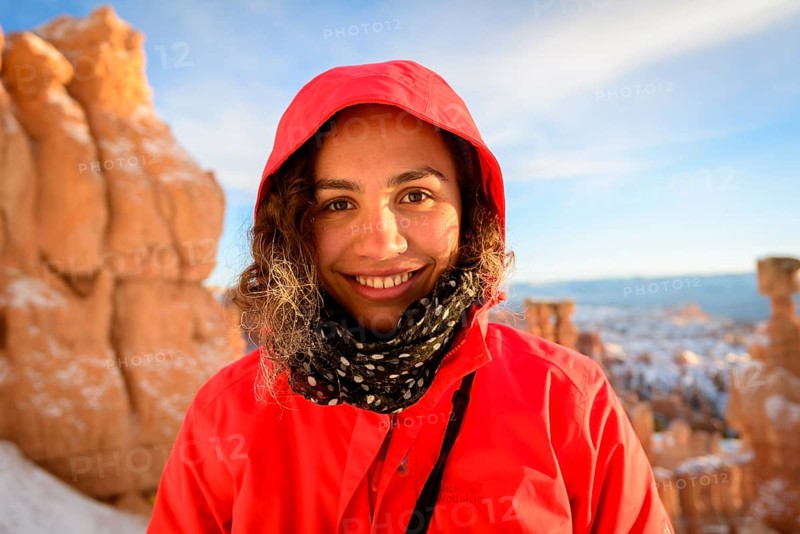 Portrait of a pretty young woman in winter clothes in front of rock needles