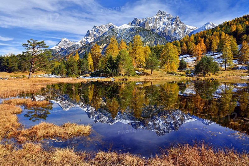 Snow-covered mountains and autumnal larch forest reflected in the Lai Nair