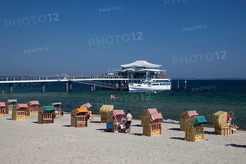 Beach chairs on Timmendorfer beach with Seeschlosschenbrucke bridge and Japanese teahouse
