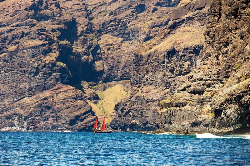 Sailing ship with red sails in front of the cliffs at Los Gigantes