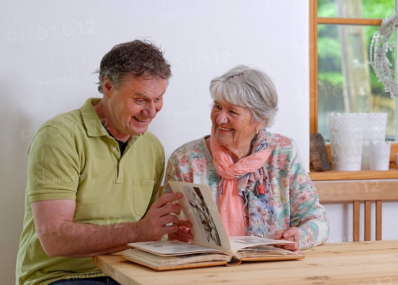 Grown-up son and elderly mother looking at a photo album