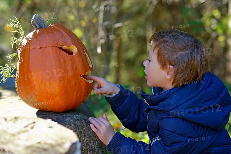Boy sitting in front of a Halloween pumpkin