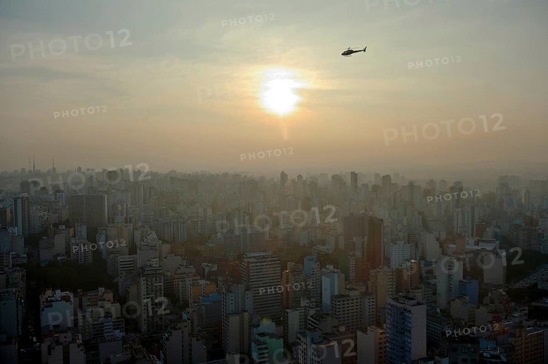 Helicopter above a cityscape with skyscrapers at sunset