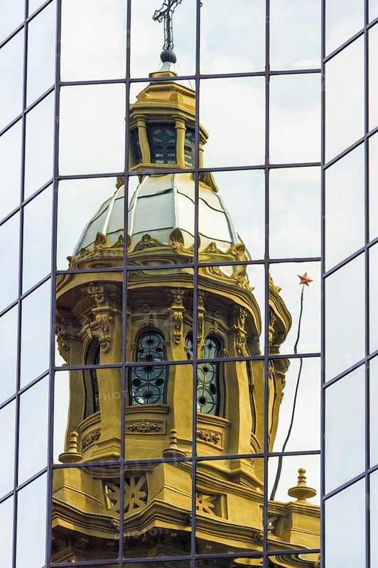 Cathedral tower reflecting in a glass building