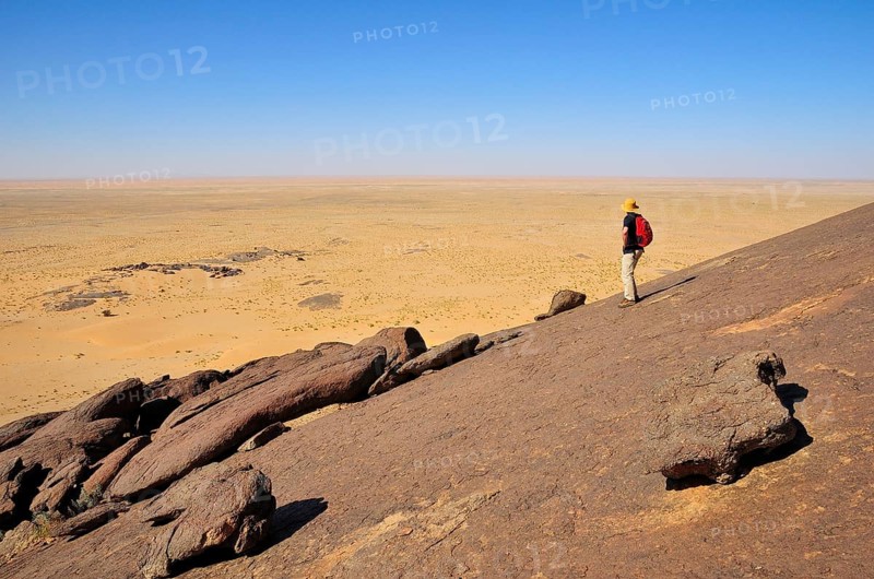 Man looking from Aicha monolith towards the flat desert