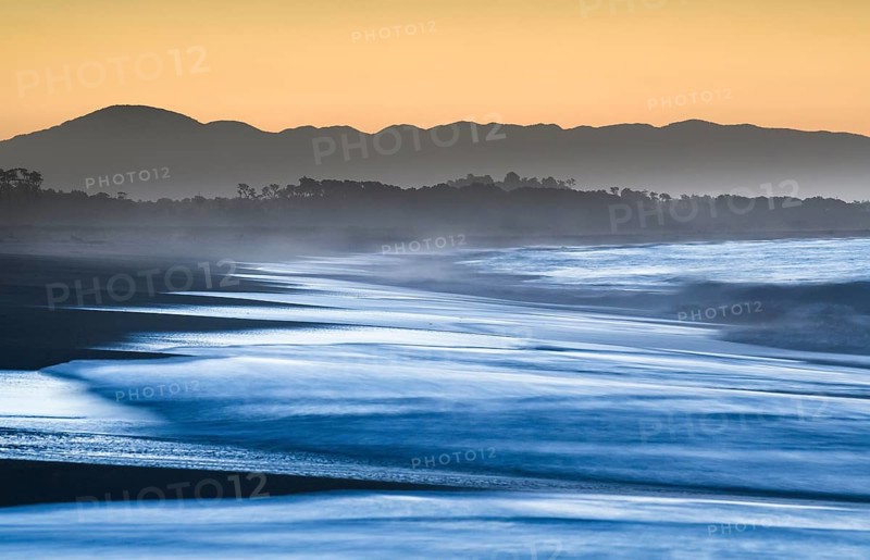 Surf with haze on a wide beach in the evening light