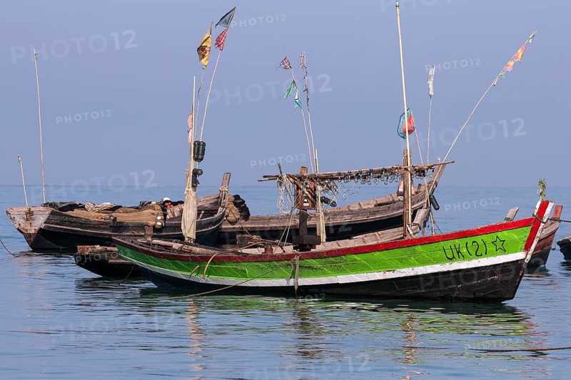 Colourful fishing boats in the sea off the beach of the fishing village of Ngapali