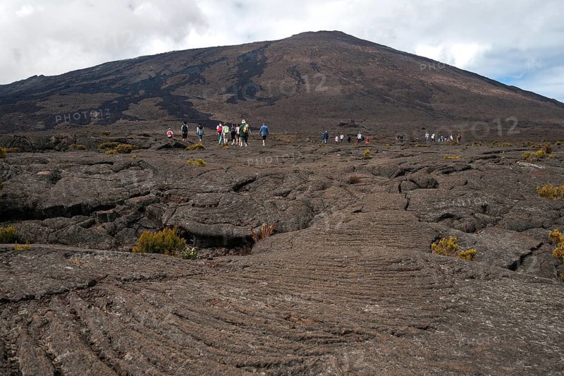 Hikers hike through lava landscape