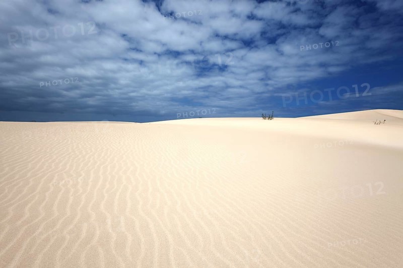 Sand dunes under blue sky with clouds