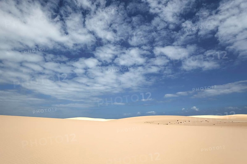 Sand dunes under blue sky with clouds