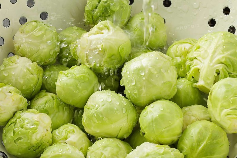 Brussels Sprouts in colander with running water