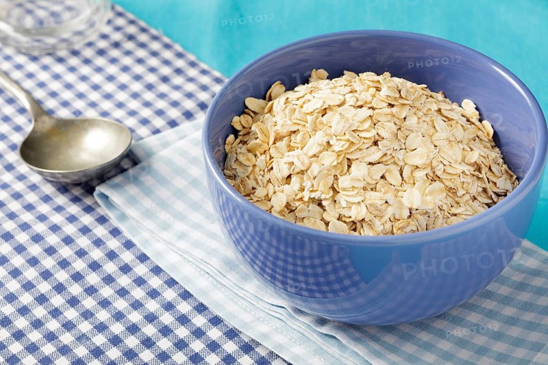 Oats flakes or porridge oats in blue bowl on breakfast table