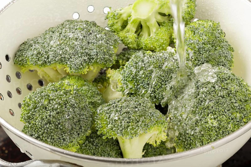 Broccoli being washed in a colander