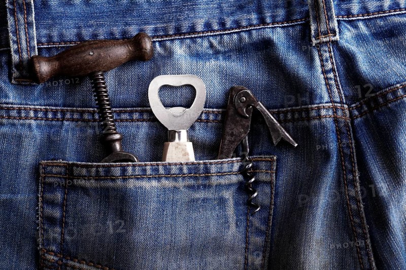 Old corkscrew and bottle openers in the pocket of jeans