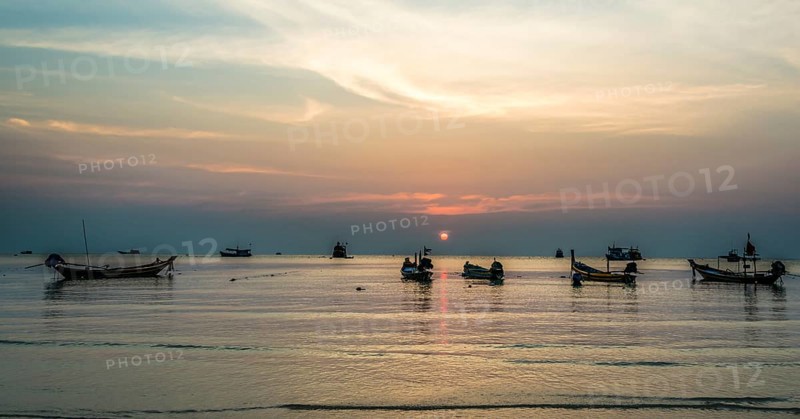 Long-tail boats in sea at sunset