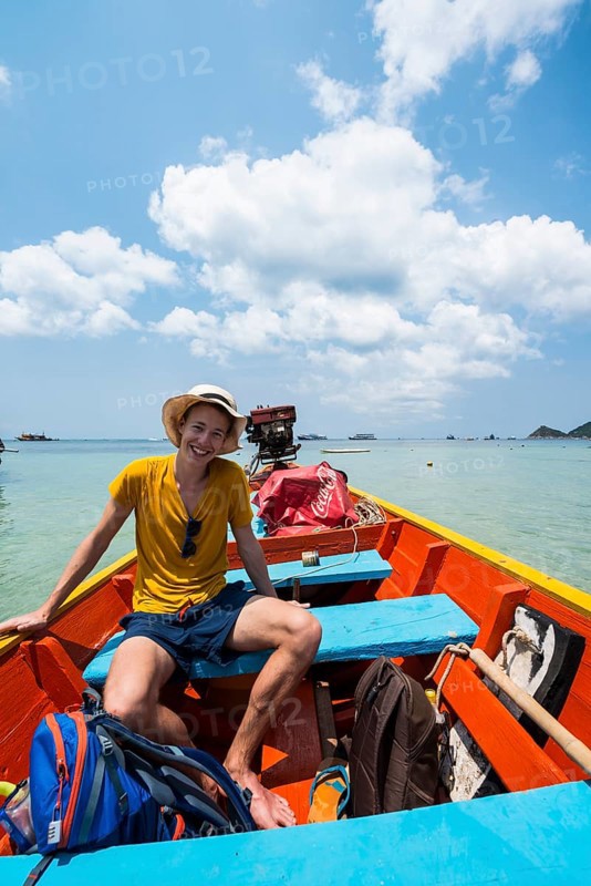 Young man sitting in longtail boat