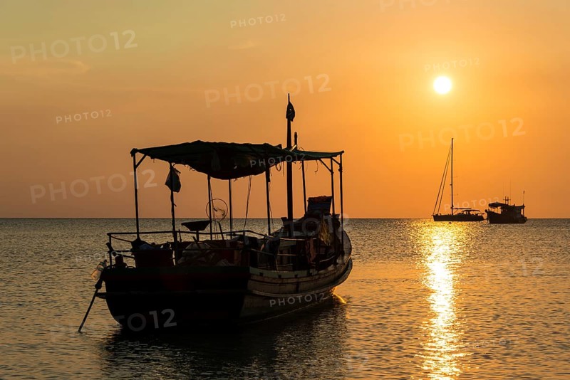 Fishing boat in sea at sunset