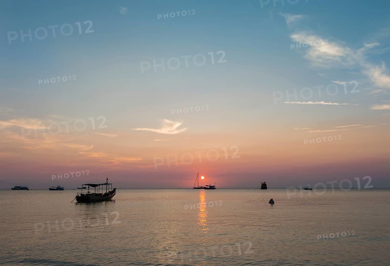 Boats in sea at sunset