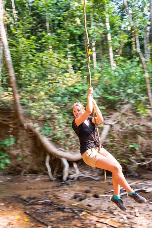Young woman swinging on a vine in the jungle