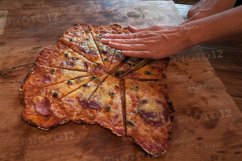 Stonebaked pizza being cut on a board