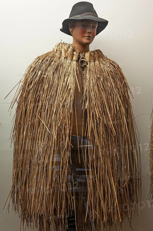 Figure of a shepherd boy with Franconian weather protection made from straw in a showcase