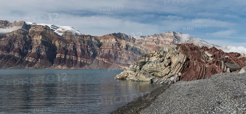 Stony beach and unfolded coloured rock strata
