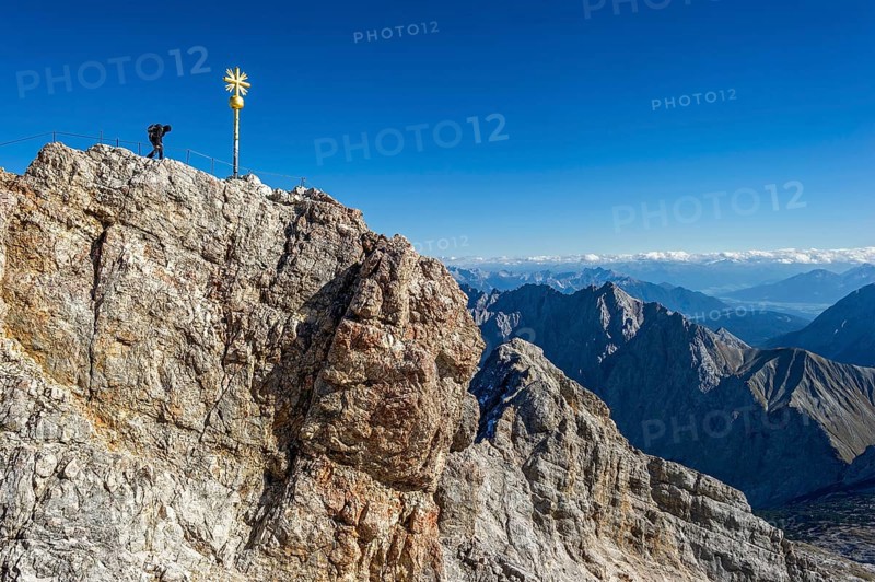 Mountaineer at the summit cross of the Zugspitze