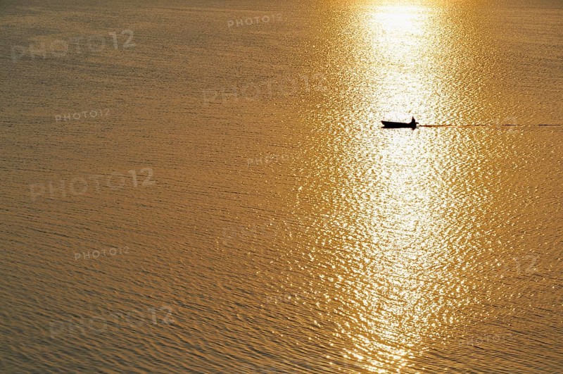 Fisherman in a motorboat at sunset