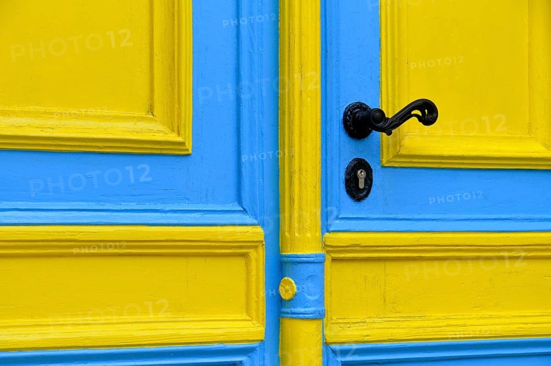 Blue and yellow painted front door with a black doorknob