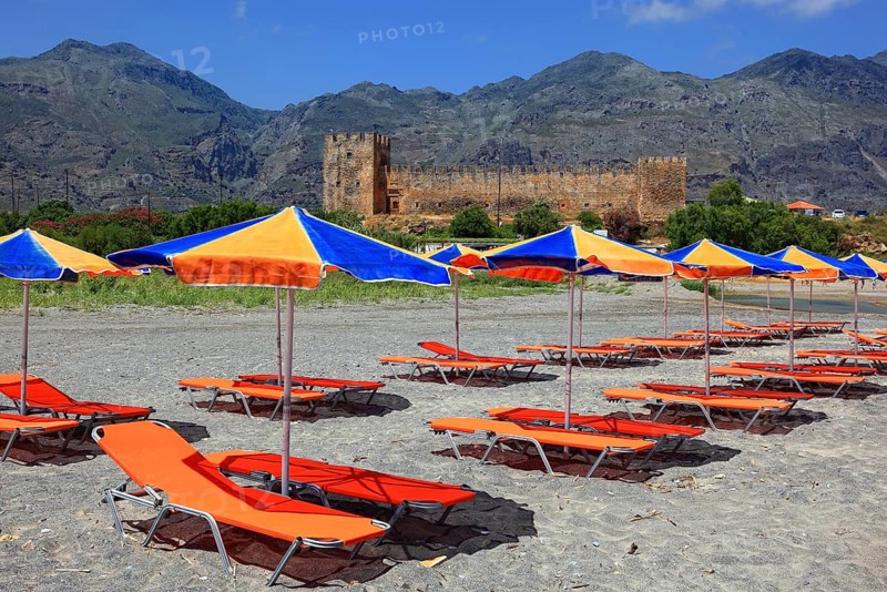 Colourful beach chairs and umbrellas in front of Frangokastello castle