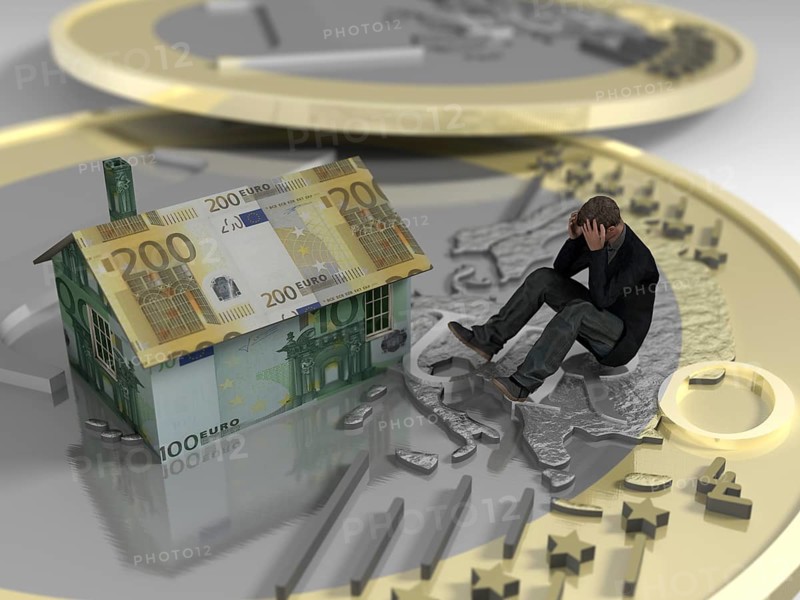 Man sitting on euro coin next to house made of banknotes