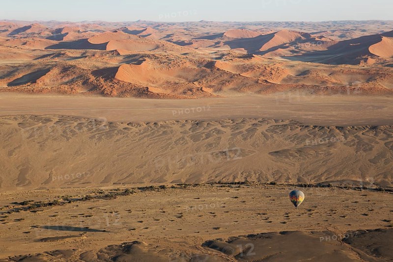 Hot-air balloon above an arid plain and the dry riverbed of the Tsauchab river at the edge of the Namib Desert