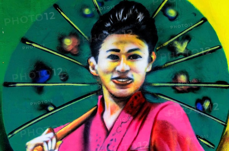Painted image of a traditionally dressed woman on a house wall
