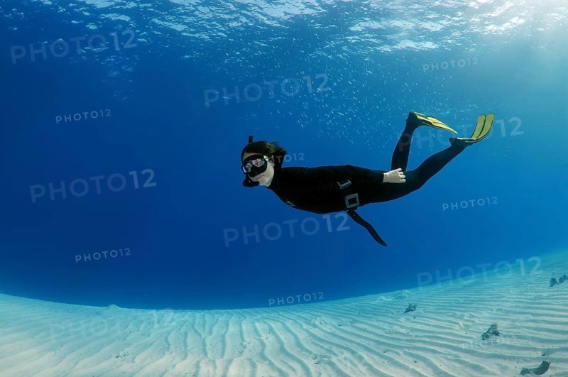 Freediver diving above a sandy bottom