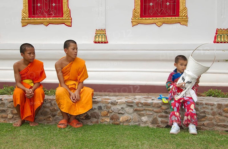Two novices and a boy holding a mask