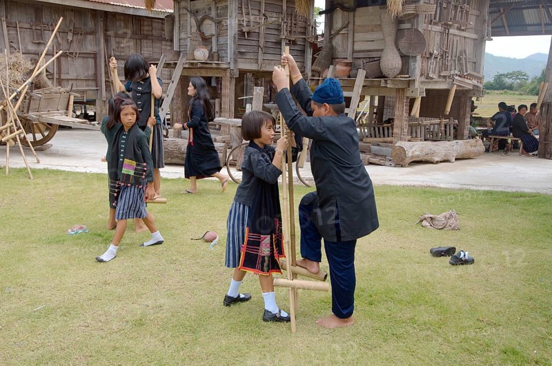 Tai Dam children walking on bamboo stilts