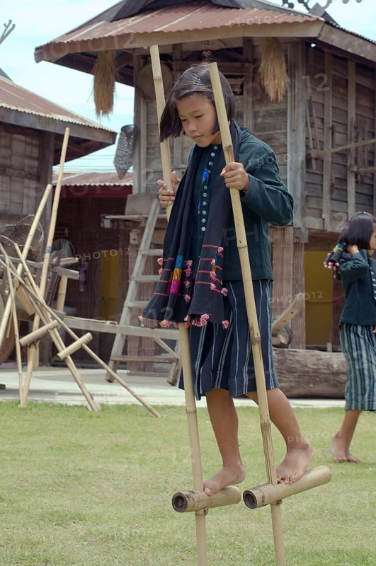 Tai Dam children walking on bamboo stilts