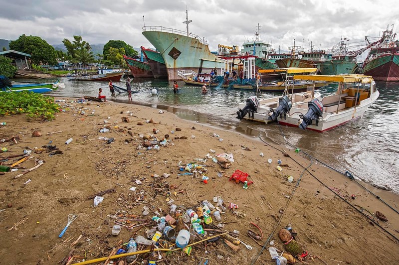 Fishing boats and beach with trash at the port of Ambon-Laha