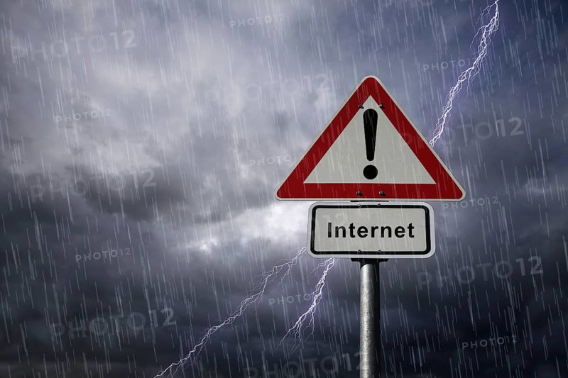 Warning and Internet road signs againt a rainy sky with lightning