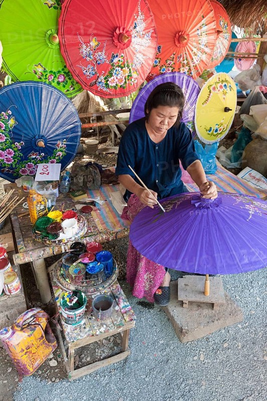 A woman is painting parasols at the umbrella village of Bo Sang