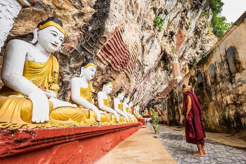 Monk looking at the seated Buddha statues