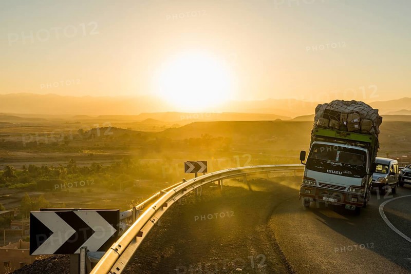 Loaded truck on curvy road in Dades Valley at sunset