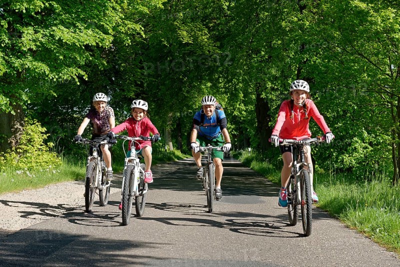 Family with children riding bicycles down avenue