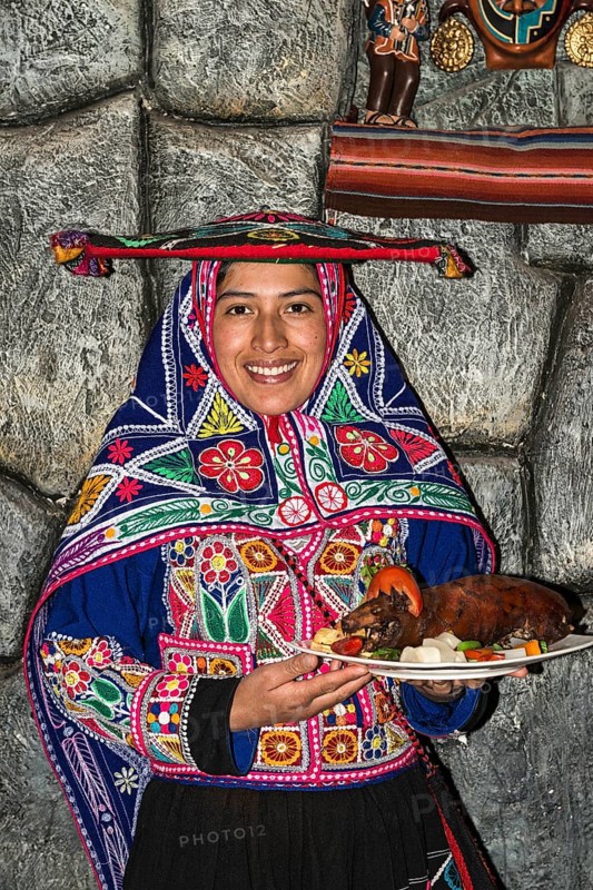 Woman serving roasted guinea pig Cuy chactado